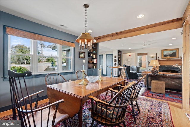 dining room with an inviting chandelier, beam ceiling, and light hardwood / wood-style flooring