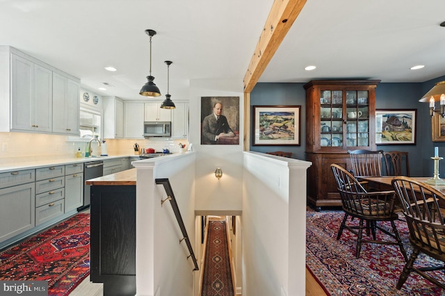 kitchen featuring gray cabinetry, decorative light fixtures, appliances with stainless steel finishes, white cabinets, and backsplash