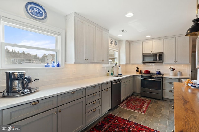 kitchen featuring stainless steel appliances, sink, gray cabinetry, and decorative backsplash