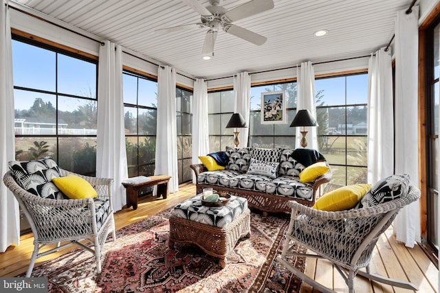 sunroom with ceiling fan and a water view