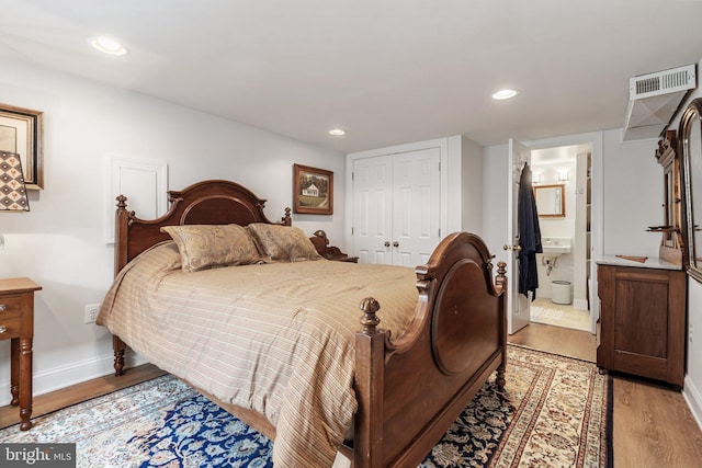 bedroom with ensuite bath, light hardwood / wood-style flooring, and a closet