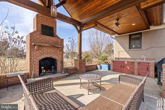 view of patio with an outdoor brick fireplace and ceiling fan