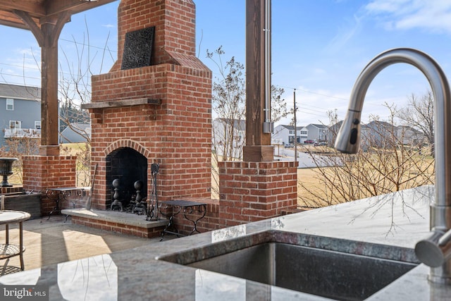 view of patio / terrace featuring an outdoor brick fireplace and sink