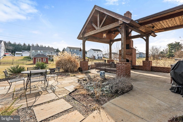 view of patio / terrace with ceiling fan, a gazebo, a fireplace, and a storage unit