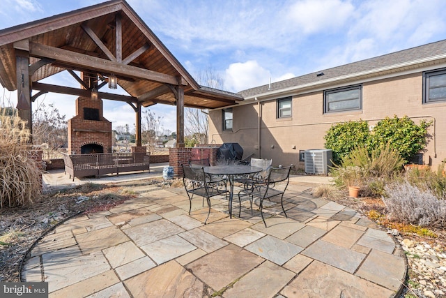 view of patio / terrace with an outdoor brick fireplace and central air condition unit