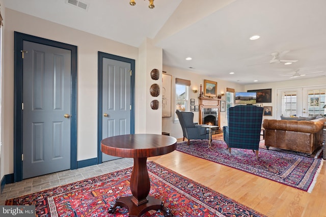 living room with plenty of natural light, french doors, ceiling fan, and light wood-type flooring