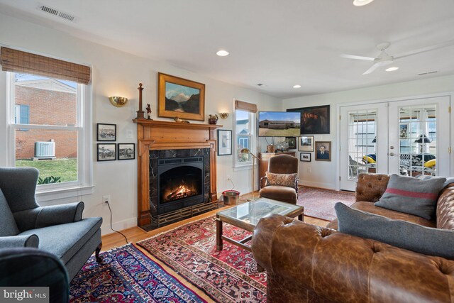 living room with french doors, a premium fireplace, and light hardwood / wood-style floors