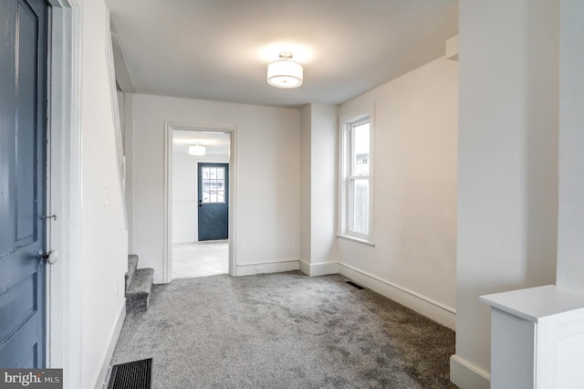 interior space featuring carpet floors, visible vents, baseboards, and stairs