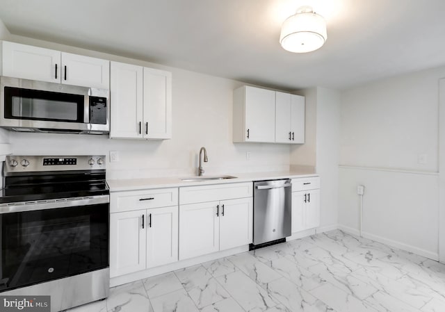 kitchen with appliances with stainless steel finishes, marble finish floor, light countertops, and a sink