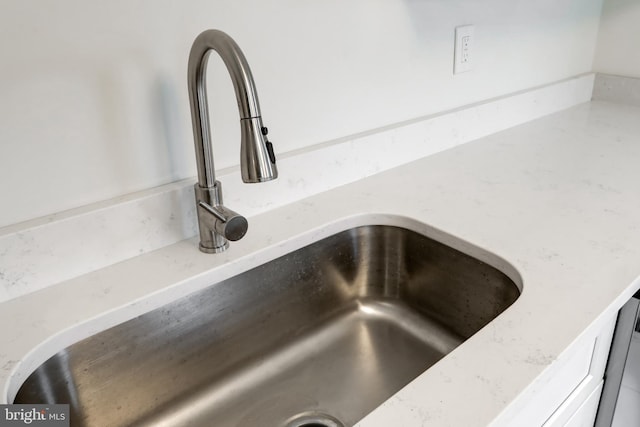 interior details featuring a sink and light stone countertops