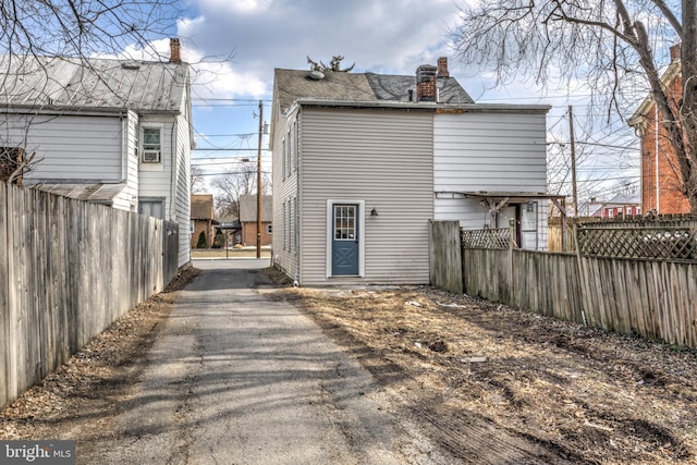 back of property with a chimney and fence