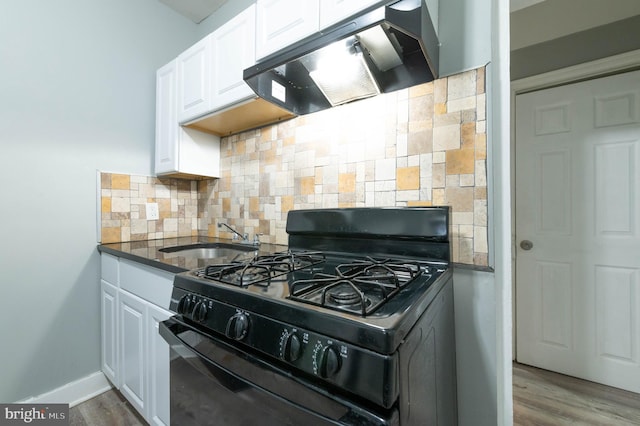 kitchen featuring sink, extractor fan, black gas stove, decorative backsplash, and white cabinets