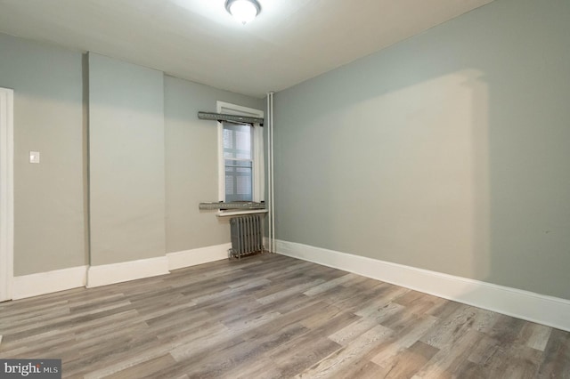 empty room featuring radiator and light hardwood / wood-style flooring