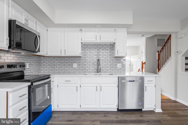 kitchen with sink, appliances with stainless steel finishes, white cabinetry, dark hardwood / wood-style flooring, and decorative backsplash