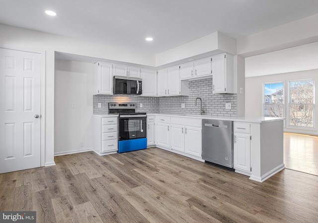 kitchen featuring sink, light hardwood / wood-style flooring, stainless steel appliances, white cabinets, and decorative backsplash