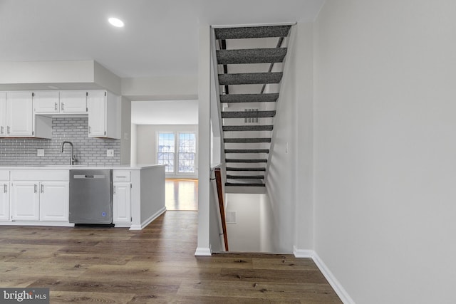 kitchen featuring sink, stainless steel dishwasher, dark hardwood / wood-style flooring, white cabinets, and backsplash