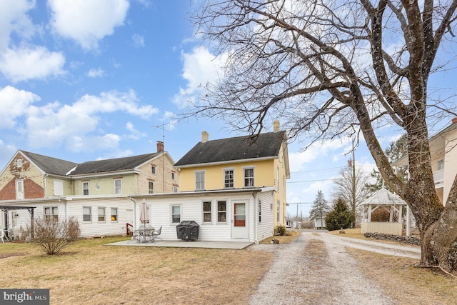 back of property featuring a patio area and a lawn