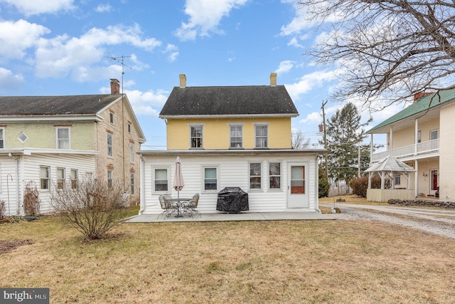 rear view of property featuring a patio and a lawn