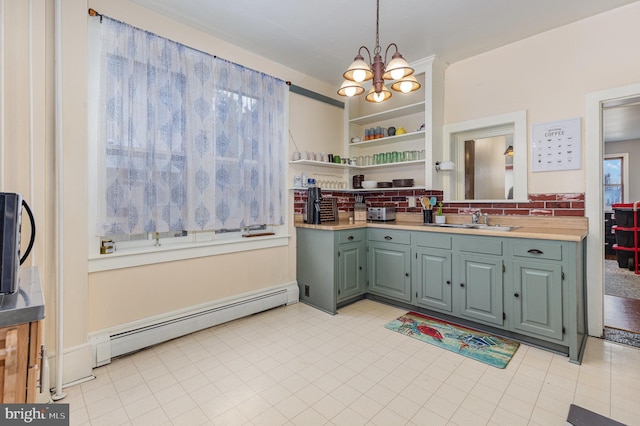 kitchen featuring pendant lighting, sink, baseboard heating, tasteful backsplash, and a chandelier