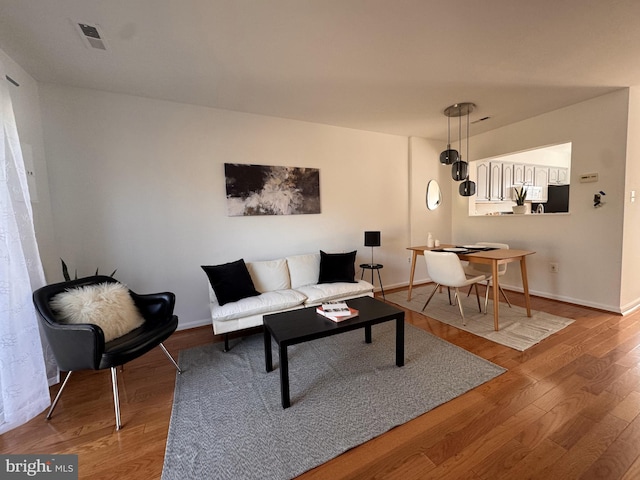 living area with visible vents, baseboards, and wood finished floors