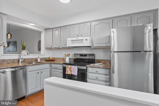 kitchen with a sink, light wood-type flooring, appliances with stainless steel finishes, and gray cabinets