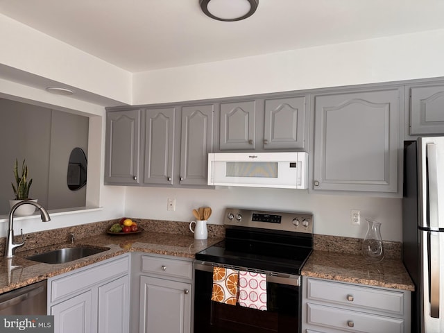 kitchen featuring a sink, stone countertops, appliances with stainless steel finishes, and gray cabinetry