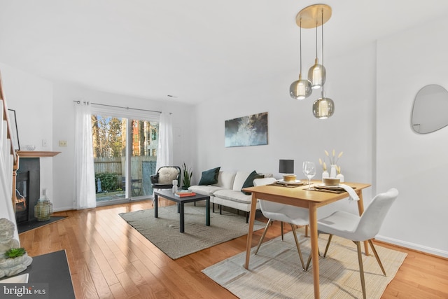 dining space with a fireplace with flush hearth, wood finished floors, and baseboards