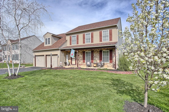 traditional-style home with covered porch, stone siding, a front lawn, and aphalt driveway