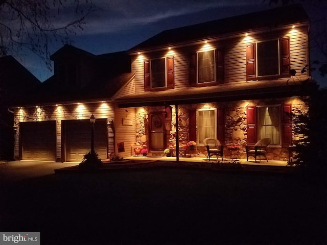 view of front of property with covered porch, stone siding, and concrete driveway