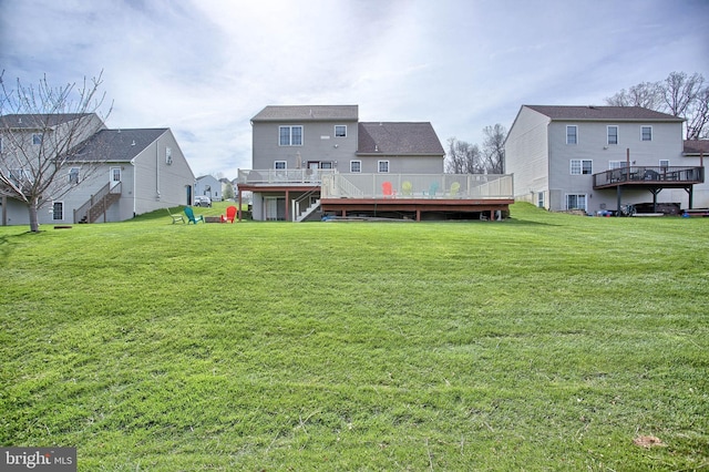 rear view of house with a yard, a wooden deck, and stairs