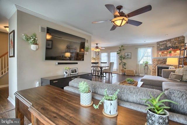 living area with visible vents, ornamental molding, wood finished floors, baseboards, and a ceiling fan