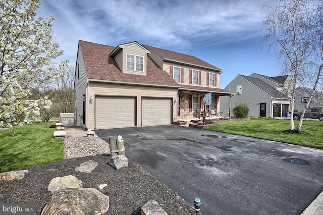 traditional home with a porch, driveway, a front yard, and a garage