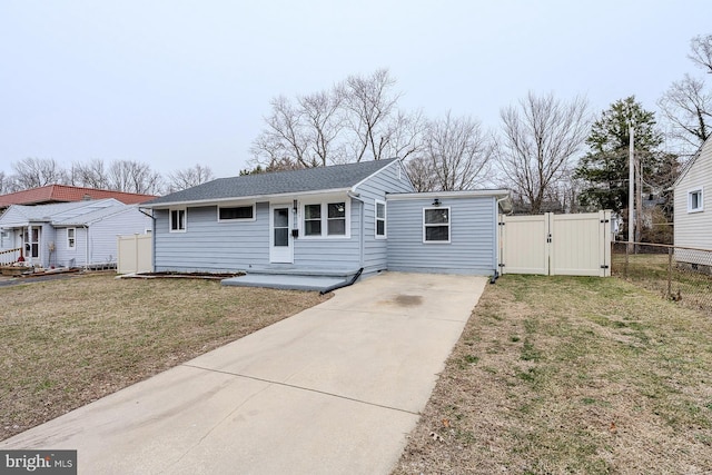 view of front facade featuring a shingled roof, fence, driveway, a gate, and a front yard