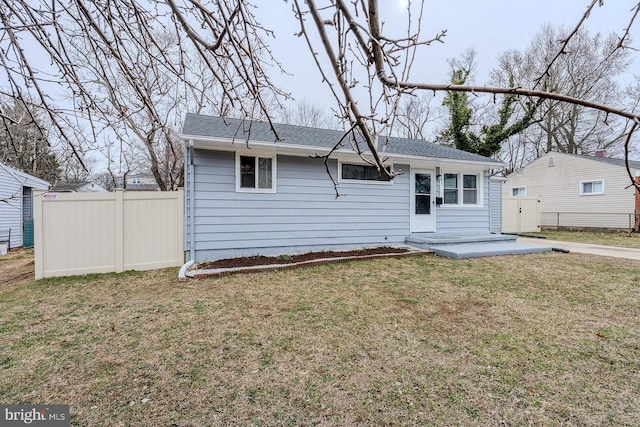 view of front of home with a shingled roof, a front yard, a patio area, and fence