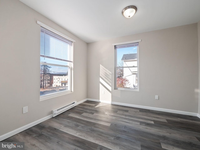 empty room featuring dark wood-type flooring and a baseboard heating unit