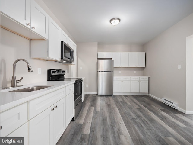 kitchen featuring sink, appliances with stainless steel finishes, white cabinetry, a baseboard heating unit, and dark hardwood / wood-style flooring