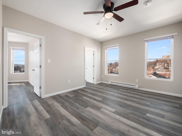 spare room featuring ceiling fan, dark hardwood / wood-style flooring, and a baseboard heating unit