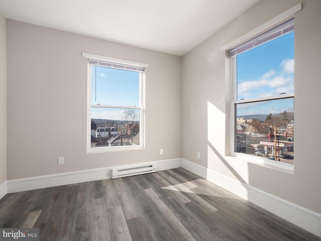 empty room featuring a wealth of natural light, dark hardwood / wood-style floors, and baseboard heating