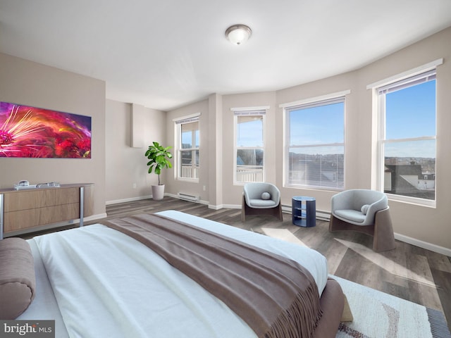 bedroom with a baseboard heating unit and dark hardwood / wood-style floors