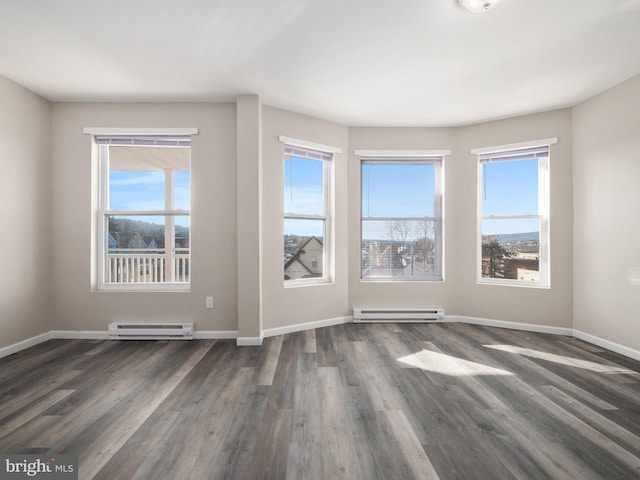 spare room with a baseboard heating unit and dark hardwood / wood-style flooring