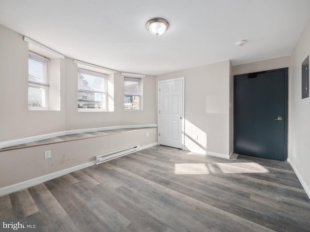 spare room featuring a baseboard heating unit and wood-type flooring