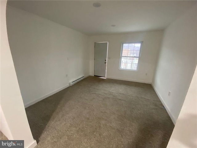 unfurnished room with carpet flooring and a baseboard heating unit