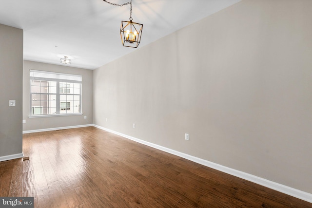 spare room with hardwood / wood-style floors and a notable chandelier