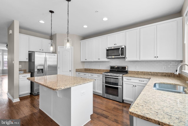 kitchen with sink, white cabinetry, decorative light fixtures, a kitchen island, and stainless steel appliances