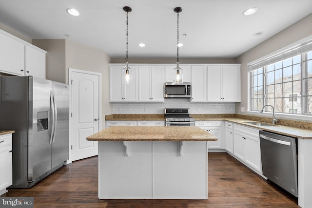 kitchen with sink, decorative light fixtures, stainless steel appliances, and a center island