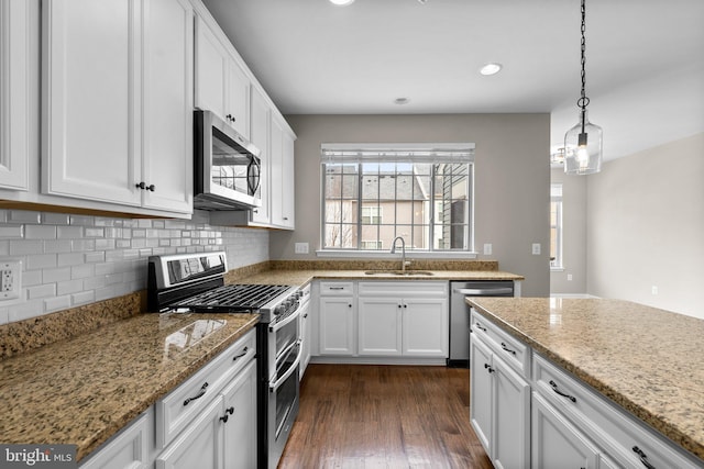 kitchen featuring sink, hanging light fixtures, stainless steel appliances, light stone countertops, and white cabinets