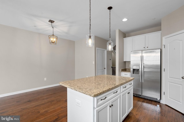 kitchen with stainless steel refrigerator with ice dispenser, dark wood-type flooring, white cabinetry, decorative light fixtures, and a kitchen island