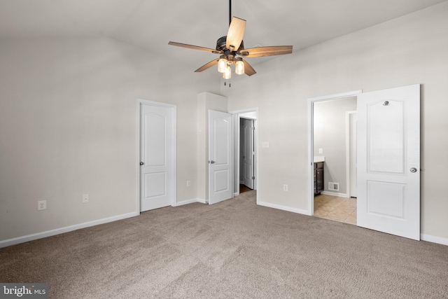 unfurnished bedroom featuring vaulted ceiling, light carpet, and ensuite bathroom