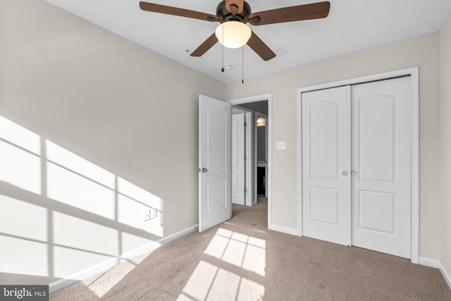 unfurnished bedroom featuring ceiling fan, a closet, and light carpet