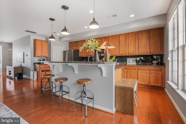 kitchen featuring hanging light fixtures, a center island, stainless steel fridge, and a breakfast bar